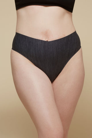 Front view image of model wearing Netherlin's black seamless high rise thong, made of aerated, quick-drying fabric and embedded with mineral fibers to inhibit odor and bacteria.