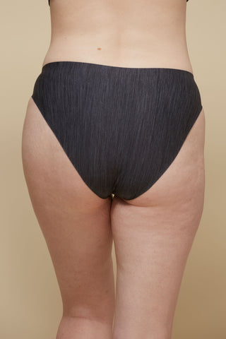 Rear view image of model wearing Netherlin's black seamless french cut brief, made of aerated, quick-drying fabric and embedded with mineral fibers to inhibit odor and bacteria.