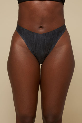 Front view image of model wearing Netherlin's black seamless thong with extra thin waistband, made of aerated, quick-drying fabric and embedded with mineral fibers to inhibit odor and bacteria.